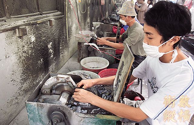 台商工廠大 批 工 人 利 用 打 磨 機 將 切 片 後 的 瑪 瑙 磨 出 天 珠 的 形 狀 。